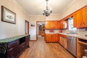 kitchen with hardwood floors, cabinets to the right, antique sideboard to the left, and a chandelier