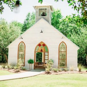 bright white church building with steeple and stained glass