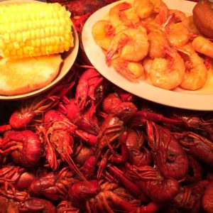 boiled crawfish with a plate of shrimp on top and another plate with corn