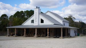 large white lodge building with front porch featuring rough wooden posts