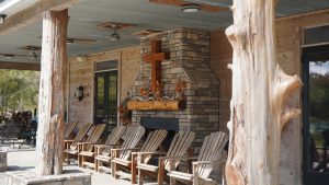 covered porch with row of Adirondack chairs and stone fireplace