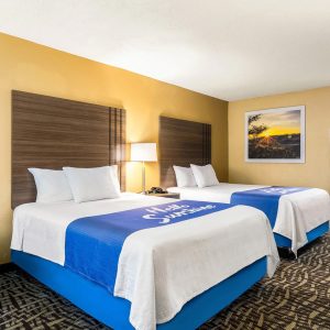 hotel bedroom featuring two beds with with blankets and blue accents