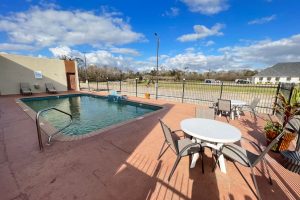 hotel pool with tables and chairs on the side