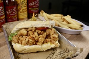 fried seafood poboy with french fries and fezzo's sauces in the background