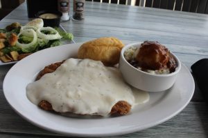 hamburger steak with white gravy, a roll and a side dish