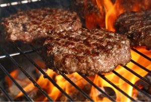 hamburger patties on a grill with fire