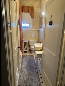 looking into bathroom with pedestal sink and black and white floors with a rug