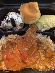 plate lunch featuring meat and rice, salad, roll, and dessert