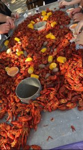 table covered in boiled crawfish with potatos, corn, and dip mixed in