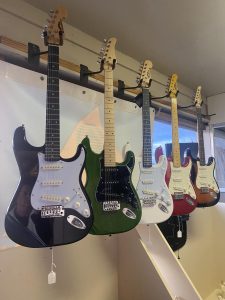 row of guitars hanging from hooks on the wall