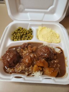 plate lunch featuring meatball stew, sweet peas, and potato salad