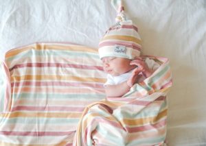 baby wrapped in blanket with knit hat