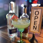 margarita with open sign and liquor bottles