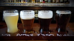 four beers in glasses lined up on a bar