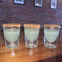 three shots lined up on a bar with salt on the rim