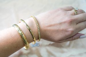 hand wearing three bracelets and a ring