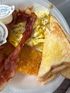 Styrofoam plate with toast, bacon, eggs, and hash brown