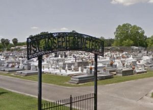 St. Joseph Cemetery black wrought-iron sign with graves in the background