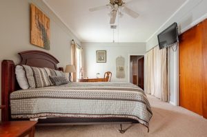 bedroom with large bed, desk in the background, and ceiling fan