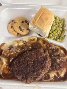 hamburger steak plate lunch with onions and gravy, cookies, roll, and sweet peas
