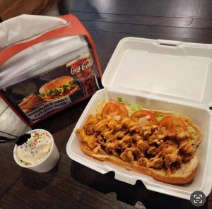 po-boy sandwich in a Styrofoam box with a napkin holder, and small ice cream