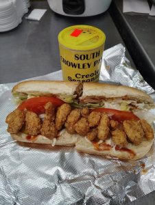 poboy sandwich on foil with a bottle of seasoning