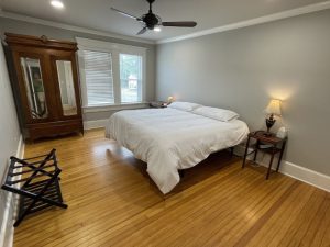 bedroom with white comforter on bed and large windows offering natural light