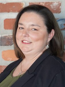 Woman's headshot in front of a brick wall