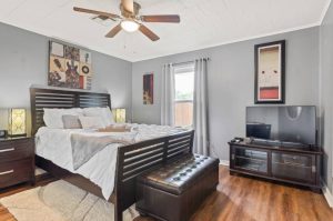 bedroom with wooden-slat bed, cushioned ottoman at the foot of the bed