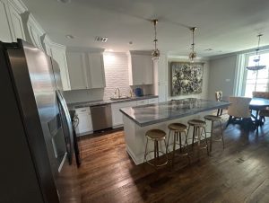 gourmet kitchen with slab granite countertops, small chandeliers, and metal stools