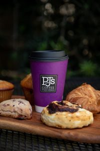 purple PJ's Coffee cup in the center with pastries surrounding it