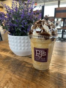 frozen coffee in the foreground with a purple flowering plant in the background