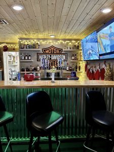 bar area with barstools and alcohol on shelves in the back