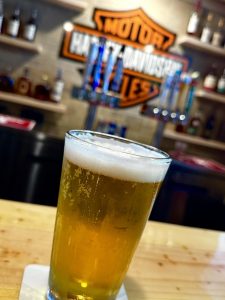 glass of bear with bar tap handles in the background