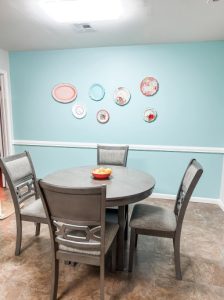dinette area with round table, four chairs, and a cheery blue paint on the wall