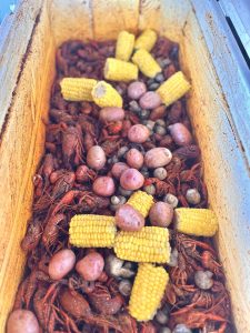 open ice chest with boiled crawfish, potatoes, and corn
