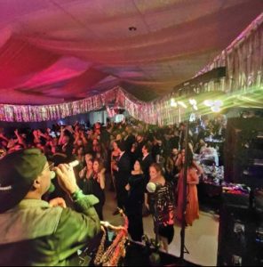 DJ in the foreground with a crowd on the dance floor