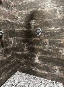 wood-look tiled shower with intricately-tiled floor