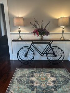 entry way table with bicycle base and two lamps with flowers on top
