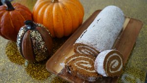 pumpkin roll covered in powdered sugar with pumpkin decorations