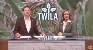Male and Female news anchor at the news desk with image of rice and TWILA logo in the background