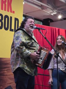Wayne Toups playing accordion and singing into a microphone.