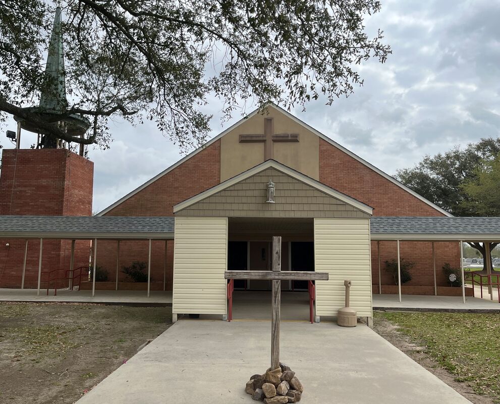 brick church building with wooden cross in front