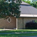 brick building with metal roof and oak tree branch in front of picture