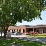 brick library building in the back with a large tree in the foreground