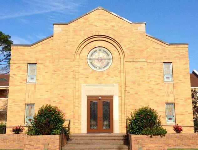 brick church building with stained glass and bushes in front