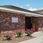 brick library building with flower bushes out front