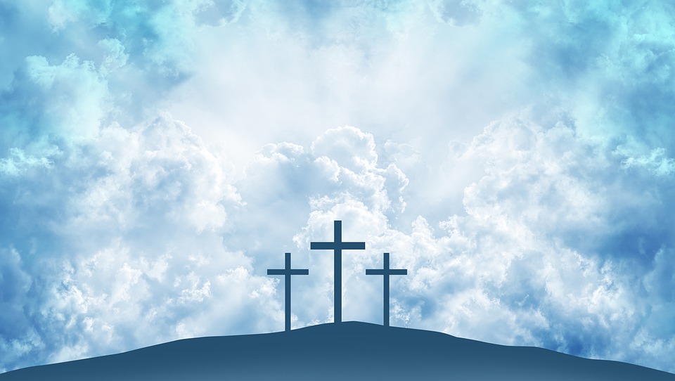 three crosses on a hill with a cloudy sky background