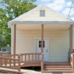 small yellow building with steps and handicap ramp out front