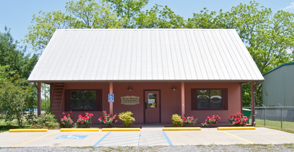 salmon-colored Acadian-style building with metal roof and flower bushes out front